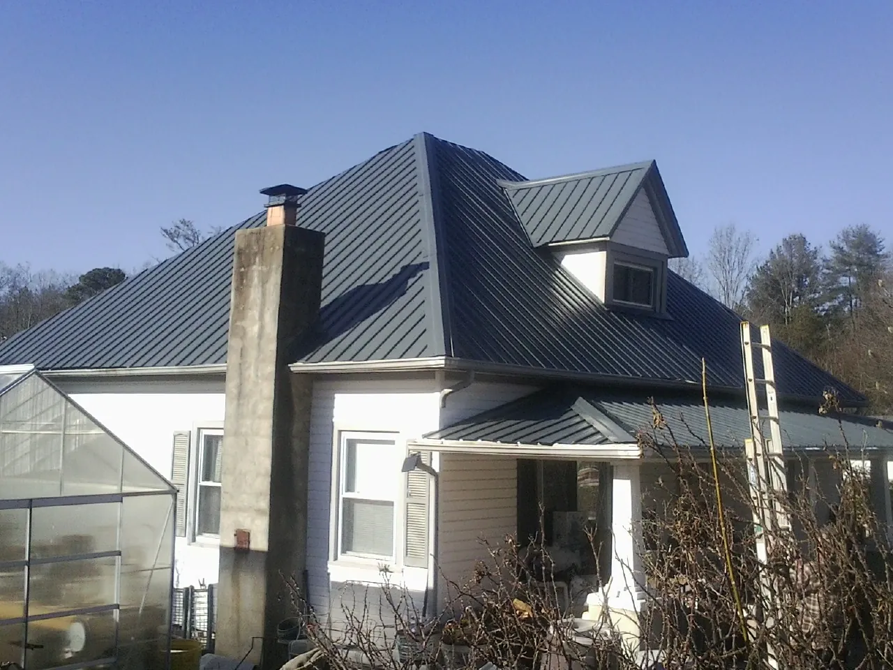 Dark blue standing seam metal roof on a white farmhouse with dormer — Slate & Tile Roof Repair by Roofing Brothers in Elizabethton