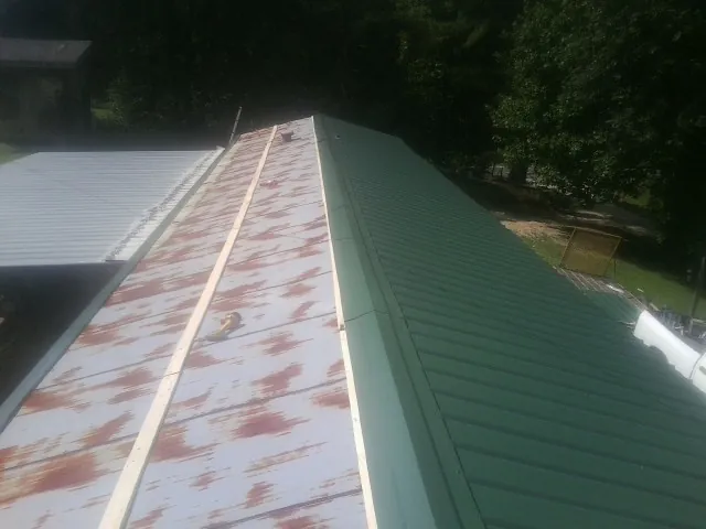 Old rusted panels beside newly installed green metal roofing — Wind Damage Roof Repair by Roofing Brothers in Elizabethton