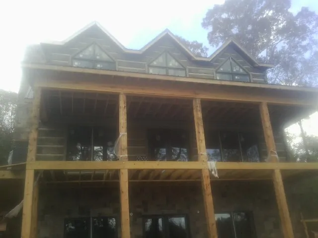 Dormers and porch framing on a large log home under construction — Roof Coating work by our crew in Elizabethton