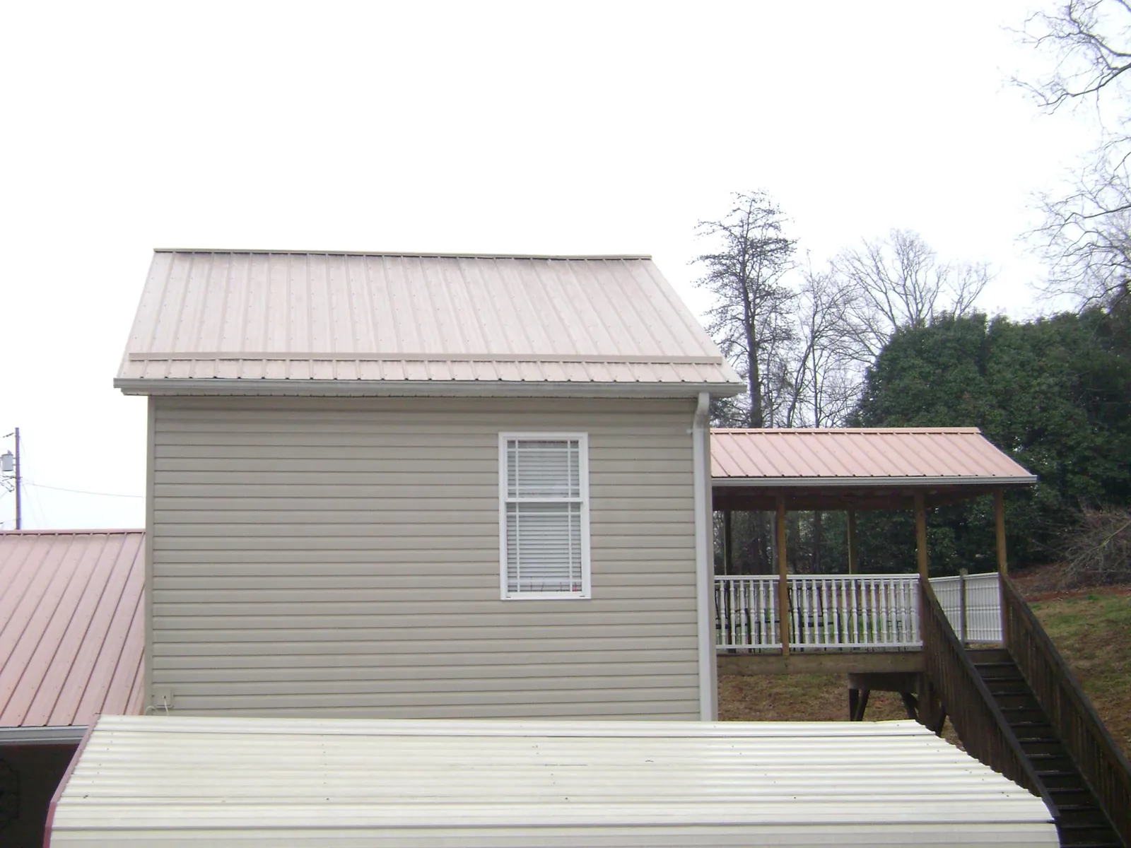 Tan metal roofs on a two story addition and attached porch, from a Roof Replacement job in Elizabethton
