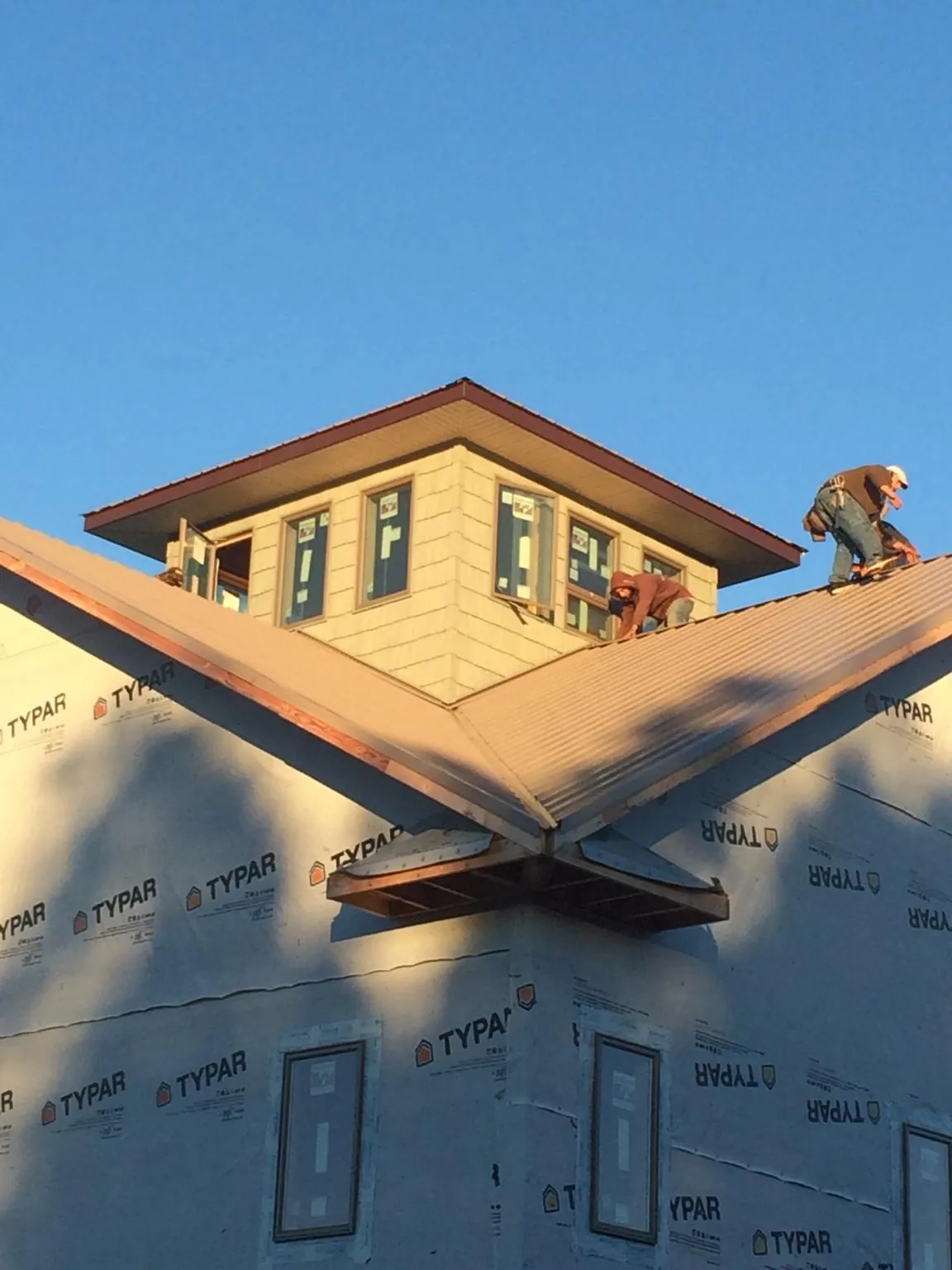 Roofers working around a rooftop cupola on a new metal roof at sunset — Roof Waterproofing in Elizabethton by Roofing Brothers